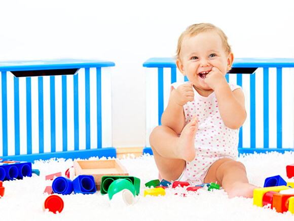 Bebé sonriendo sentado al lado de sus juguetes