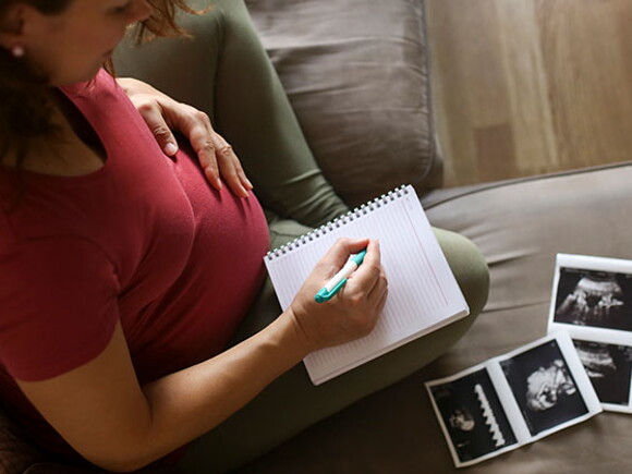 Mamá con un cuaderno mirando la ecografía de su embarazo múltiple.